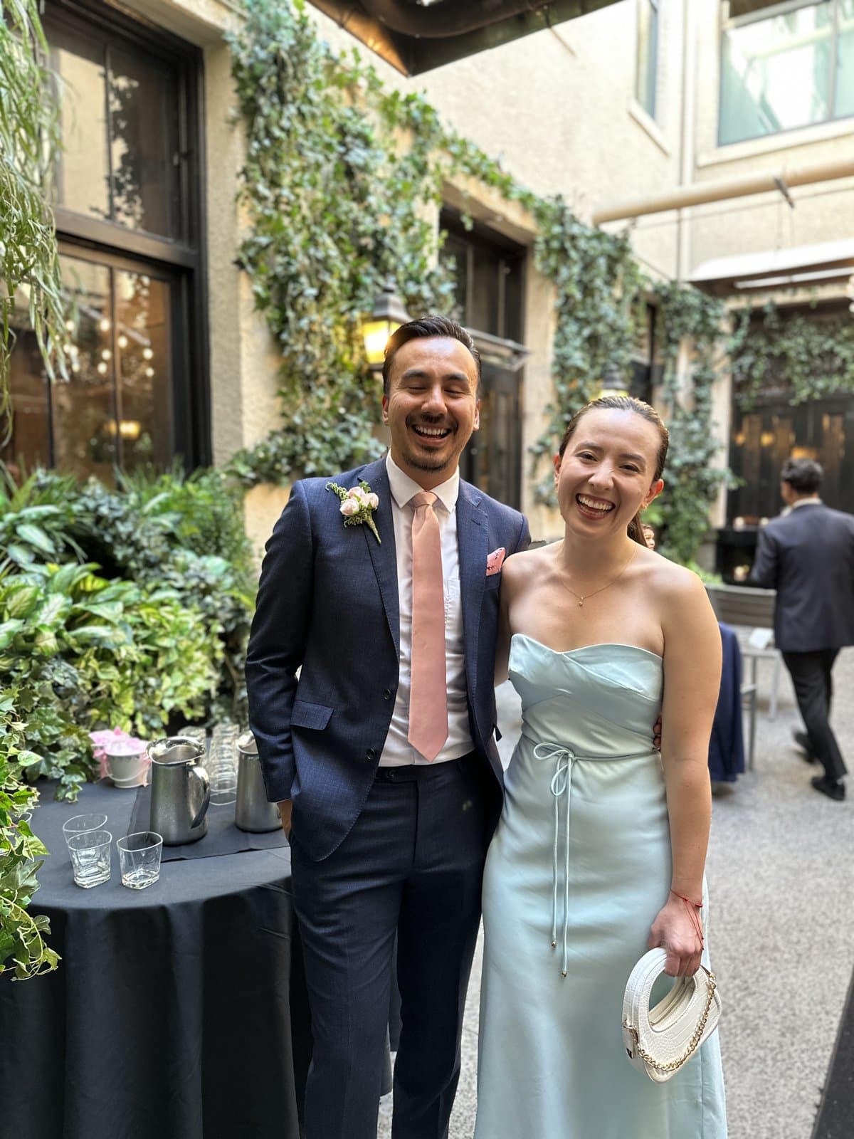 Monica and Jaime, the two founders of Fluid, laughing side by side in an ivy-covered courtyard